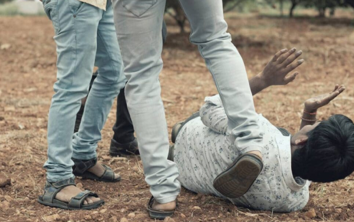 mine owners abusing a worker by kicking him while he is on the ground