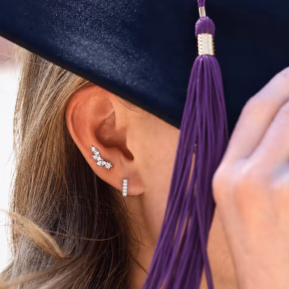 Graduate wearing a graduation cap and tassel with delicate diamond ear cuff earrings