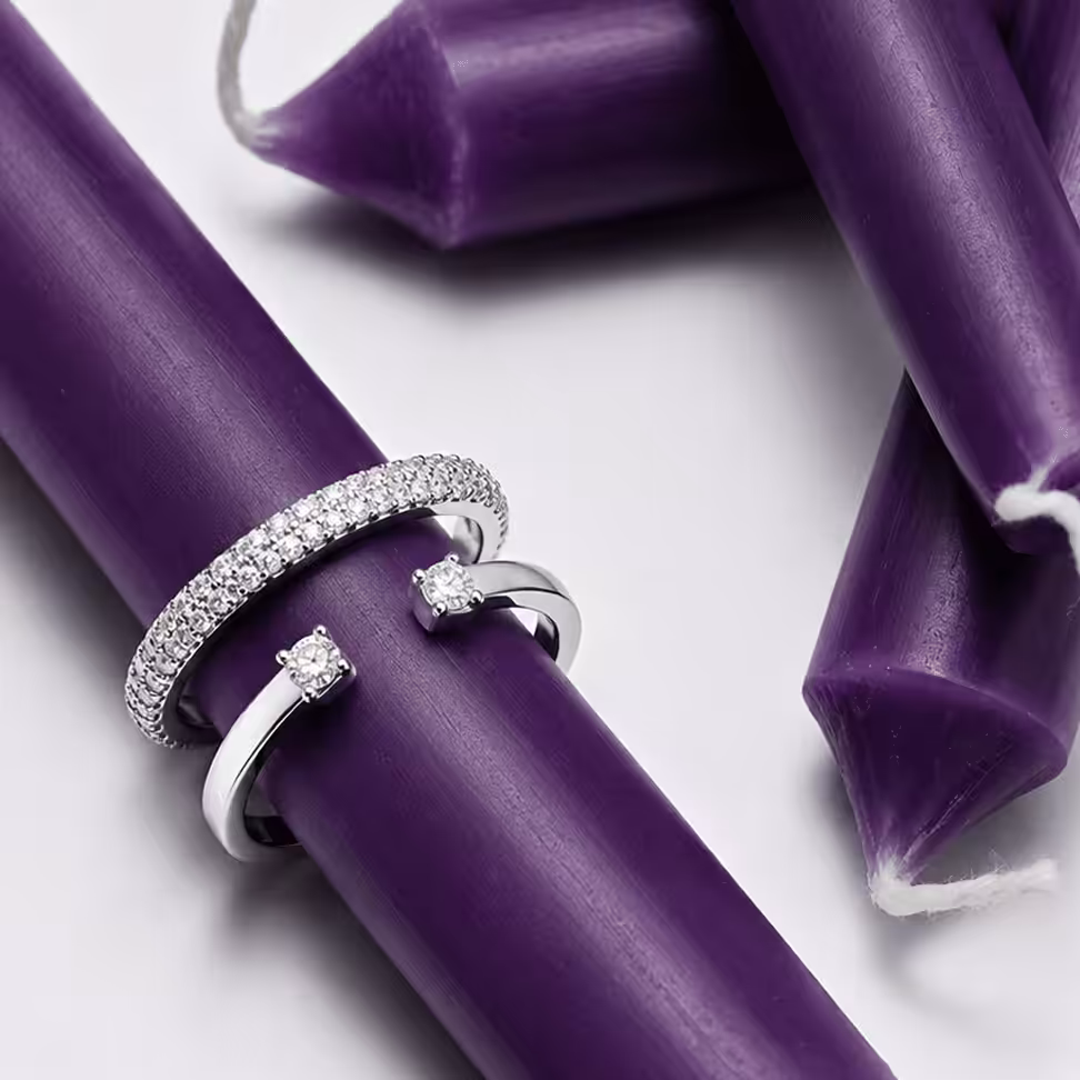 Silver and white gold diamond rings stacked on a purple Hanukkah candle - Hanukkah holiday fine jewelry gifts