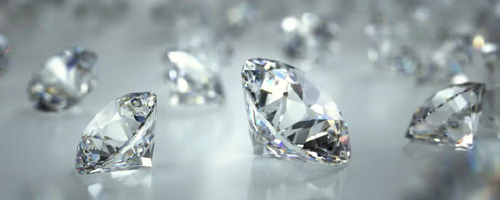 Loose round brilliant lab-grown diamonds reflecting light on a bright surface.