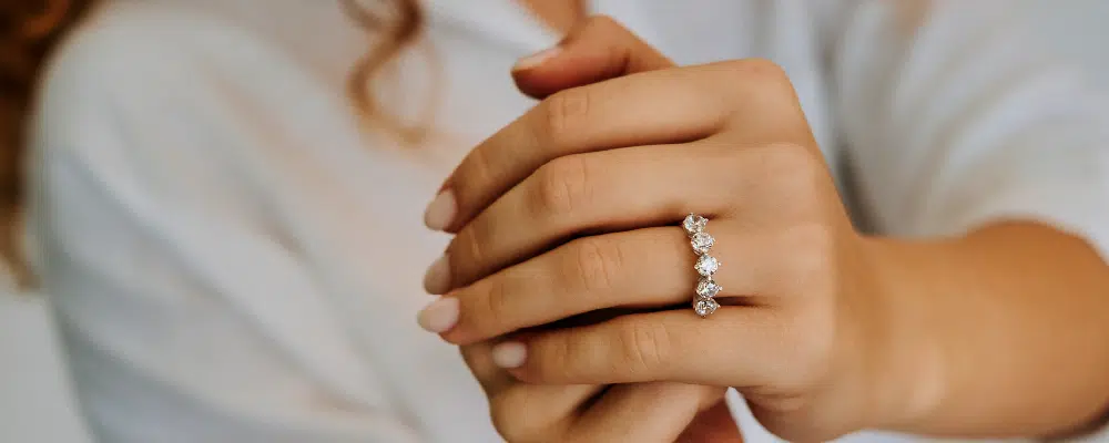 Elegant white gold 5-stone diamond anniversary ring showcased on a woman's clasped hands