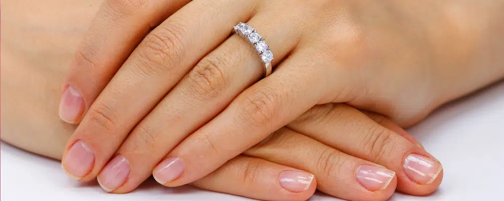 A brilliant five-stone diamond ring resting on hands to show diamond proportion and finger coverage