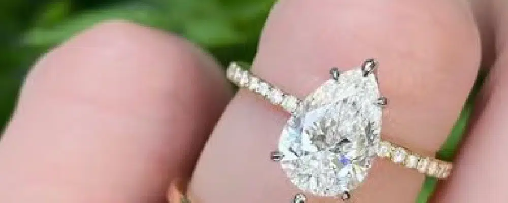 Large pear shaped diamond engagement ring with a hidden halo and pavé band to maximize carat appearance on the finger.