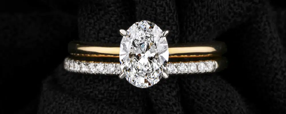 Oval cut solitaire engagement ring in yellow gold elegantly matched with a thin diamond pave wedding band style