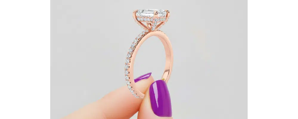 Close-up profile view of an emerald cut rose gold hidden halo engagement ring
