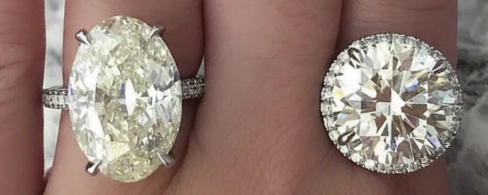 Side-by-side size comparison of an elongated oval diamond ring and a round solitaire ring with a hidden halo.
