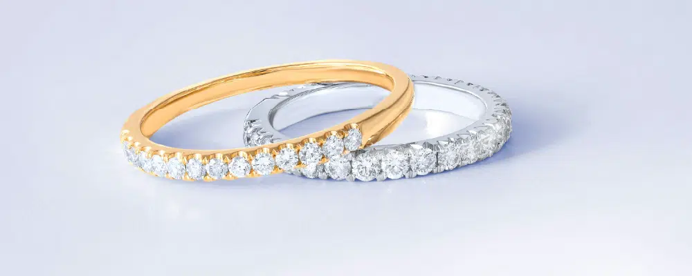 Two pave-set diamond eternity wedding bands in contrasting yellow gold and white gold, illustrating a mixed metal wedding ring style for modern couples.