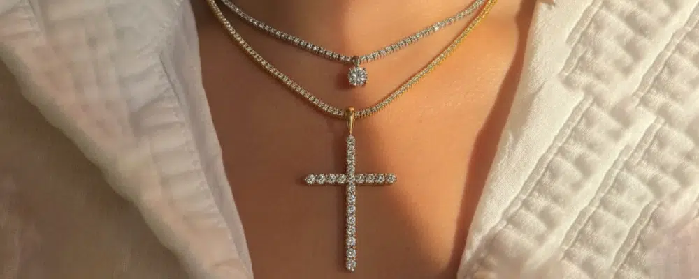 Layered lab-grown diamond tennis necklace and cross pendant in mixed 18k yellow and white gold.