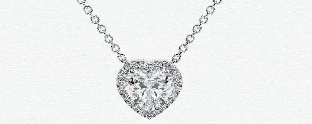 A comparison of yellow gold and white gold diamond heart pendants resting on red roses, perfect for anniversary or romantic gift symbolism