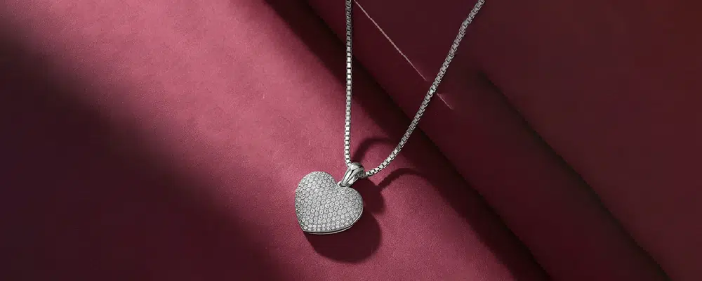 A woman wearing an elegant open heart diamond necklace on a silver chain against a dark red dress, perfect for formal occasions.