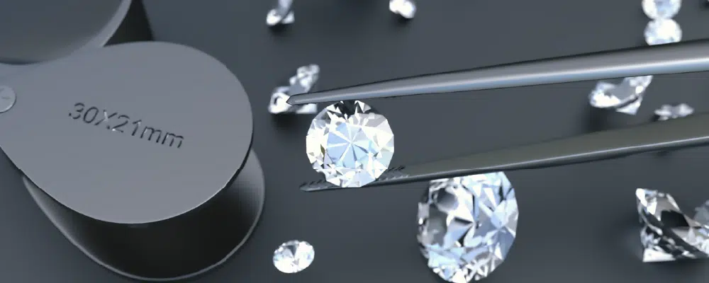 Jeweler using professional tweezers to inspect a high quality loose round diamond next to a jewelry loupe