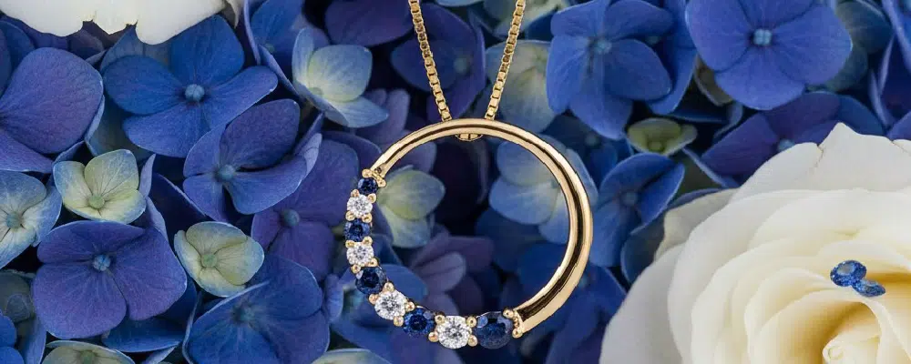 Round brilliant lab-grown diamond and blue sapphire open circle pendant necklace in 14k yellow gold.