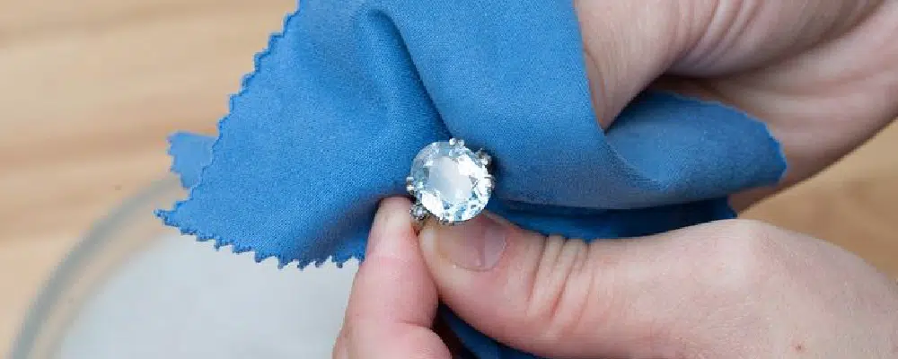 Polishing an oval-cut gemstone engagement ring with a lint-free microfiber cloth to maintain its shine and luster.