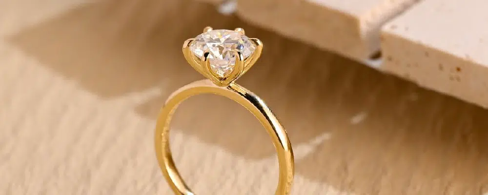 Delicate thin gold solitaire engagement ring with a round cut diamond and 6-prong setting showcasing a minimalist and dainty band style.