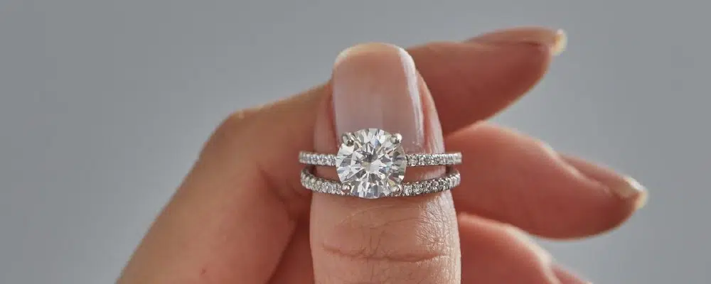 Close-up of a stacked diamond engagement ring and wedding band being assessed for size adjustment and comfort fit.