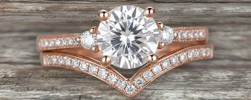 Round lab-grown diamond three-stone engagement ring with chevron pavé band in rose gold.