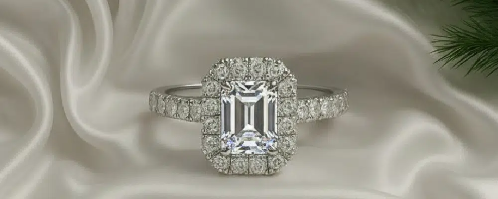 A classic Gold emerald cut diamond halo engagement ring with a pavé band