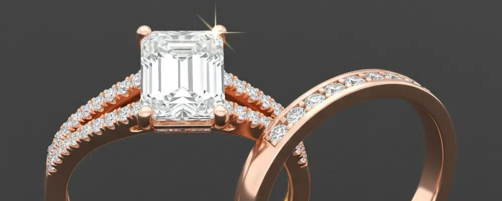 A rose gold emerald cut engagement ring with a split shank pavé band paired with a matching diamond wedding ring