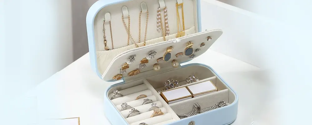 Storing diamond engagement rings and gold necklaces safely inside a compact light blue velvet jewelry organizer box