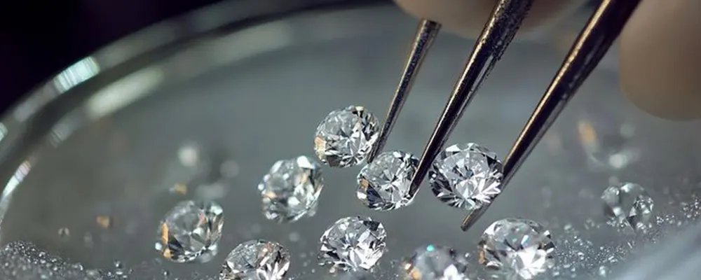 Colorless round brilliant cut diamonds being sorted with tweezers for fine jewelry settings.