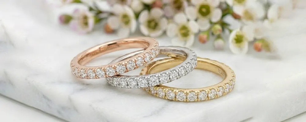 Round brilliant lab-grown diamond eternity bands in rose, white, and yellow gold.
