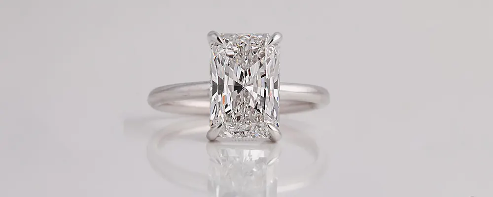 A classic solitaire engagement ring showcasing a colorless, elongated radiant cut lab grown diamond in a sleek white gold four-prong setting.
