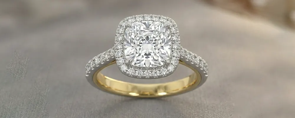 A classic cushion cut diamond halo engagement ring with a delicate pave band and a two-tone yellow gold inner shank.