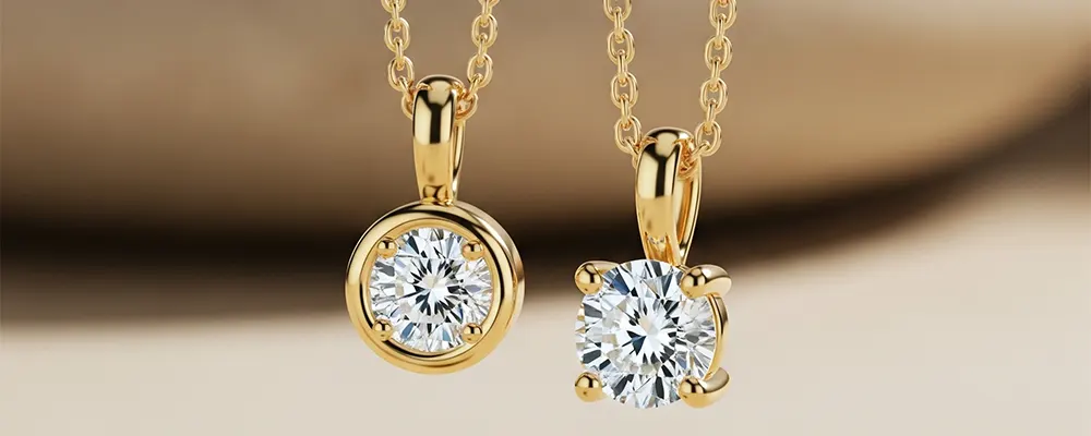 A comparison of a bezel set and a prong set round diamond pendant necklace in yellow gold.