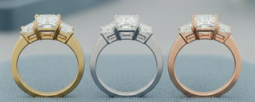 Profile and gallery view of three stone emerald cut engagement rings crafted in yellow gold platinum and rose gold bands