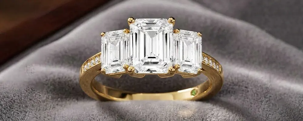 A luxurious three stone emerald cut diamond engagement ring with a yellow gold band