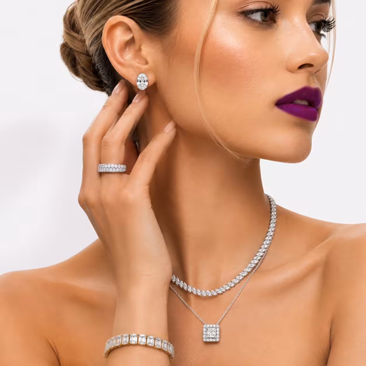 Model wearing a white gold marquise diamond tennis necklace, oval diamond stud earrings, and a diamond ring to showcase fine lab-grown jewelry.