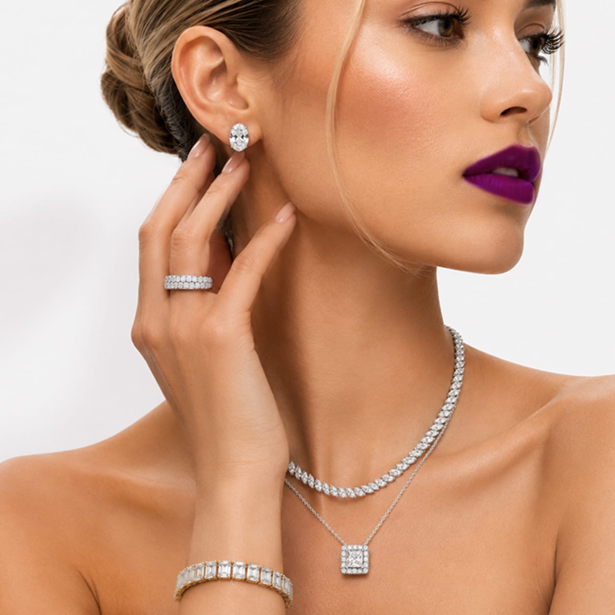 Model wearing a white gold marquise diamond tennis necklace, oval diamond stud earrings, and a diamond ring to showcase fine lab-grown jewelry.