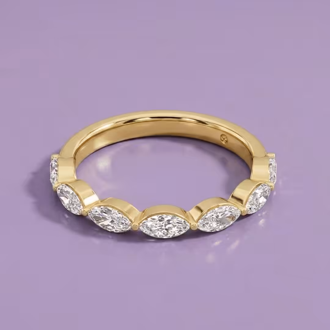 Yellow gold anniversary ring featuring marquise-cut lab-grown diamonds set horizontally on a purple background.